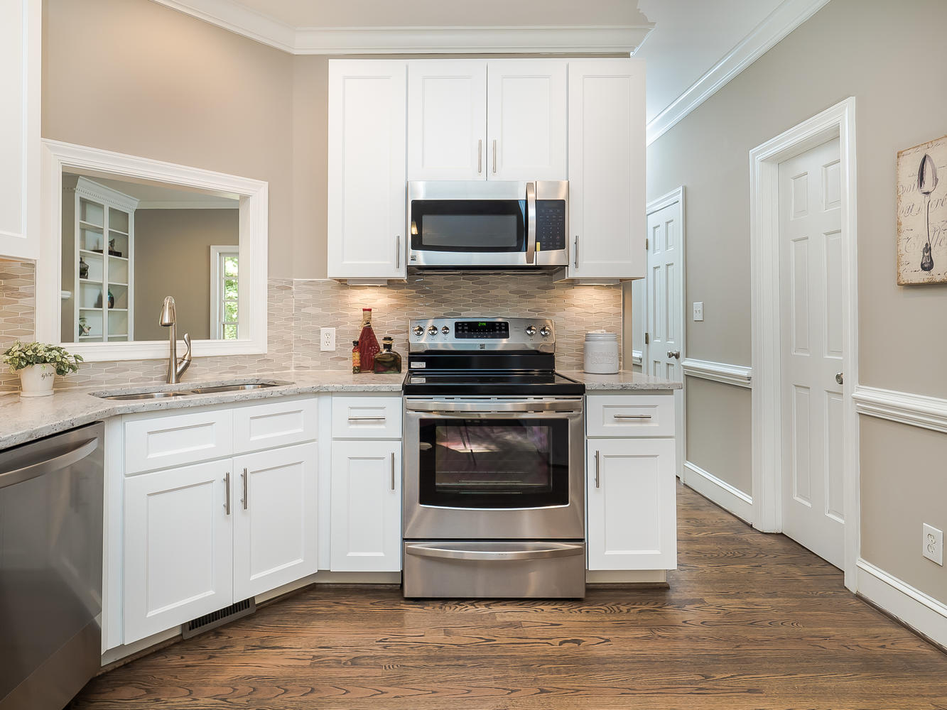 White cabinets surrounding a stainless steel range and microwave
