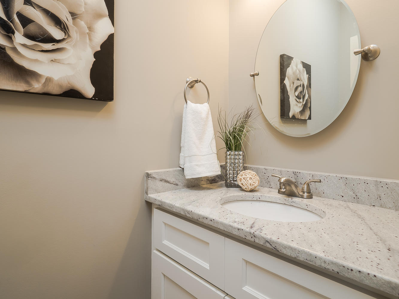 White vanity cabinetry with a light countertop and oval mirror