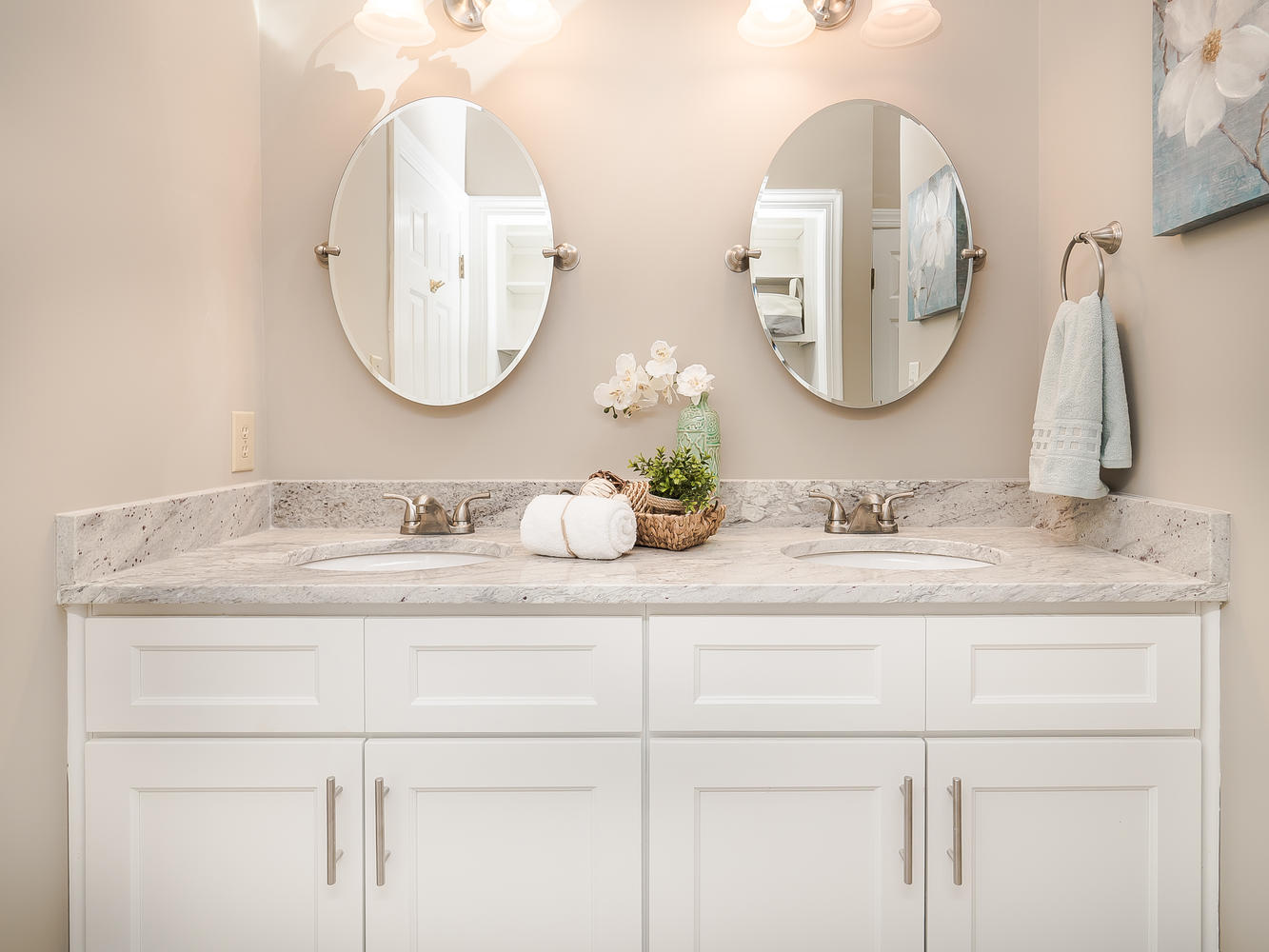 White double vanity with two oval mirrors and metal cabinet pulls