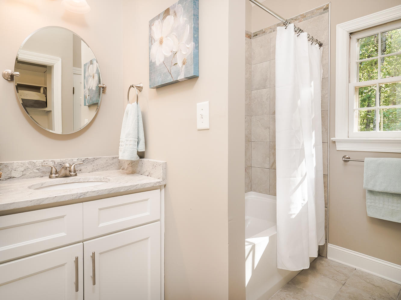 White vanity cabinetry beside the bathroom tub and shower