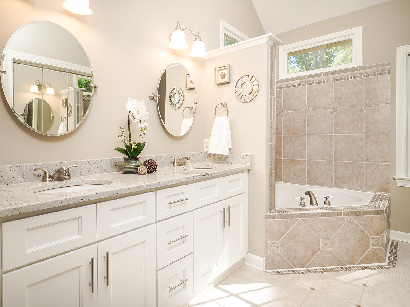 White double vanity with drawer storage beside a tiled bathtub